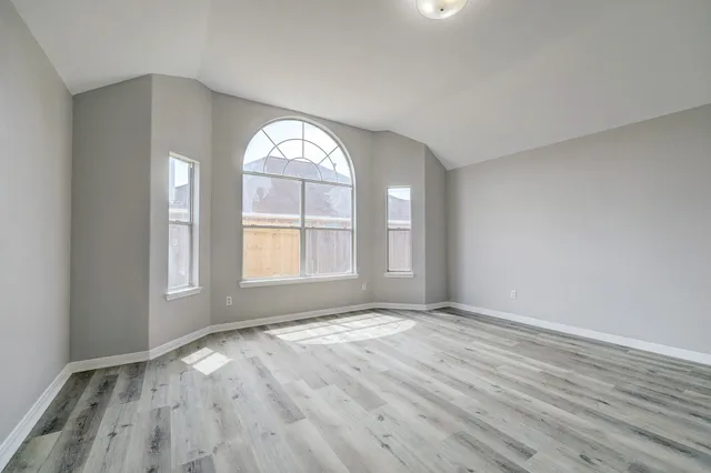 an empty room with wooden floor and windows