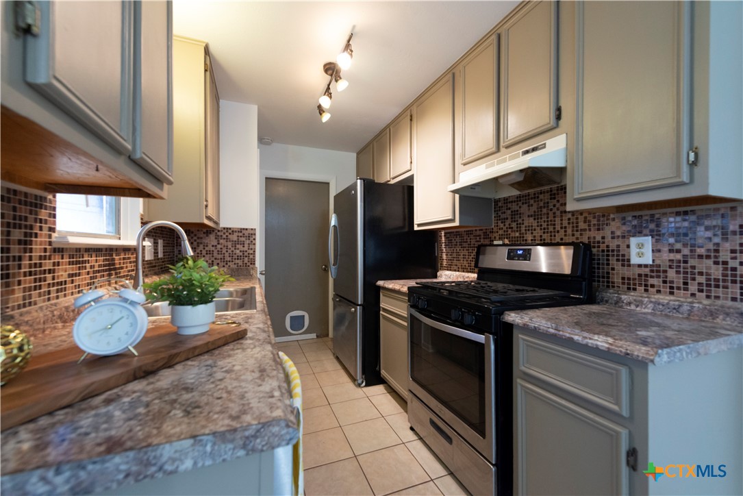 1201 Ridgemont Drive Killeen, TX 76549 - Photo 9 of 21 a kitchen with granite countertop a stove refrigerator and microwave