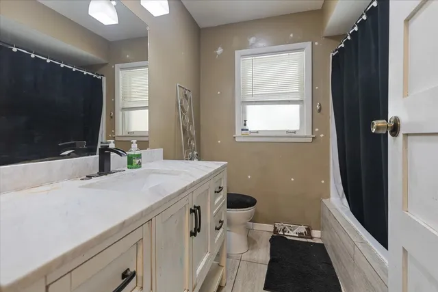 a bathroom with a sink a toilet a mirror and window