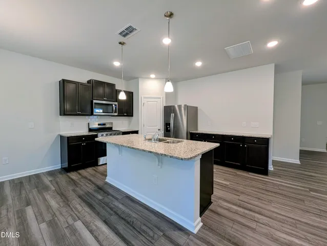 a kitchen with stainless steel appliances granite countertop a sink a stove top oven a counter space and cabinets