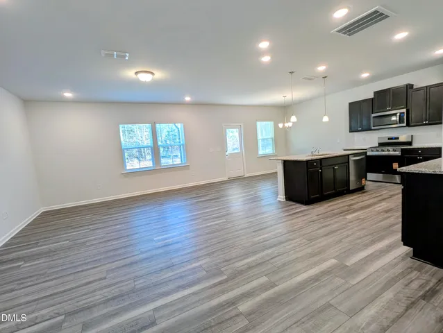 a view of kitchen with kitchen island granite countertop a large counter top stainless steel appliances and cabinets