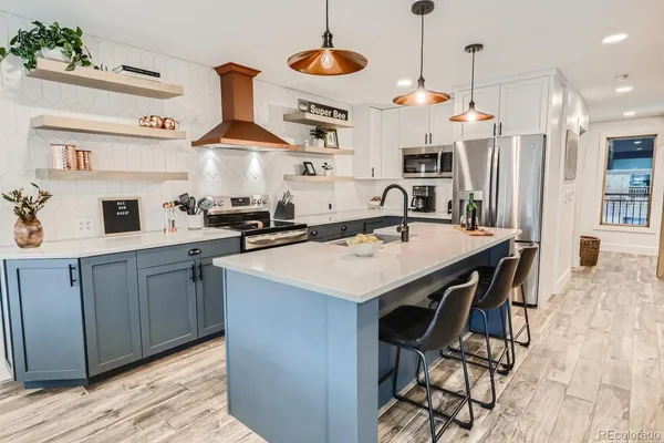 a kitchen with stainless steel appliances granite countertop a sink a stove and chairs