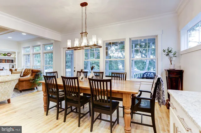a view of a dining room and livingroom with furniture wooden floor a chandelier