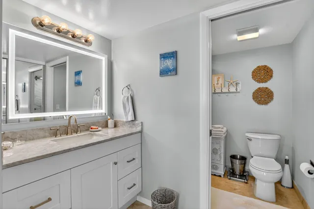 a bathroom with a granite countertop toilet sink and mirror