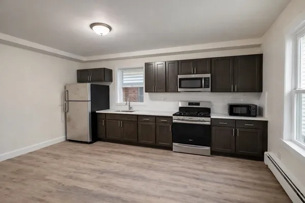 a kitchen with granite countertop a refrigerator and a stove top oven