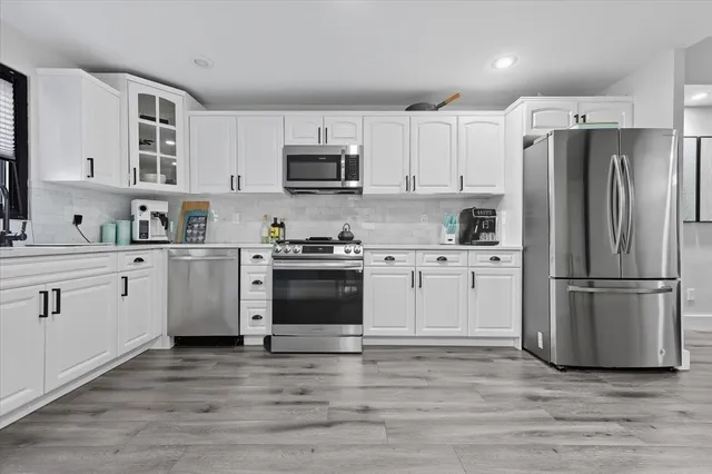 a kitchen with white cabinets and stainless steel appliances
