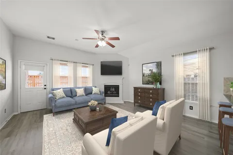 a living room with furniture a fireplace a flat screen tv and a window