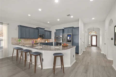 a kitchen with stainless steel appliances granite countertop a table chairs sink refrigerator and cabinets