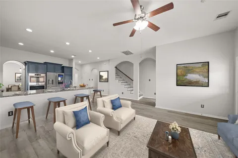 a living room with furniture kitchen view and a wooden floor
