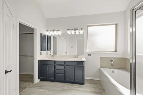 a bathroom with a tub a sink and mirror