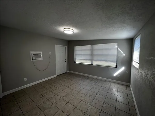 an empty room with windows and fireplace