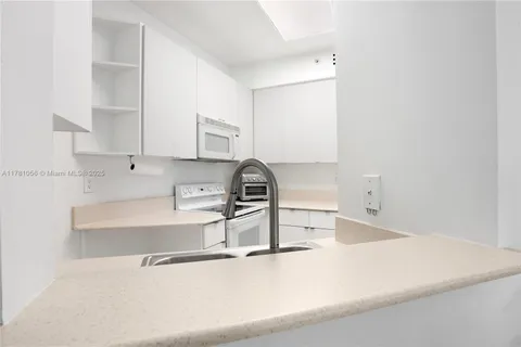 a kitchen with kitchen island a sink and a stove with white countertops