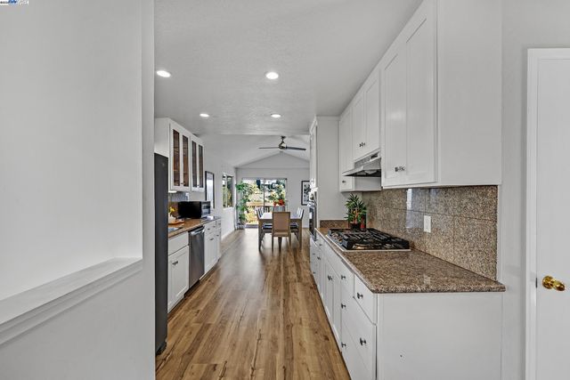 a kitchen with granite countertop kitchen island wooden floor center island stainless steel appliances and cabinets