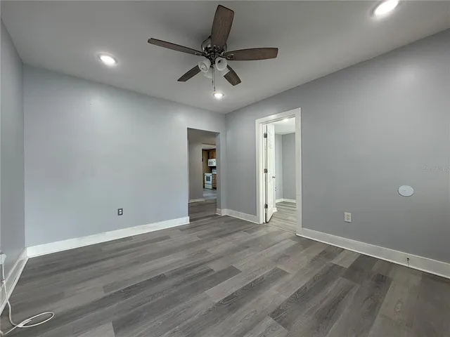 an empty room with wooden floor and a ceiling fan