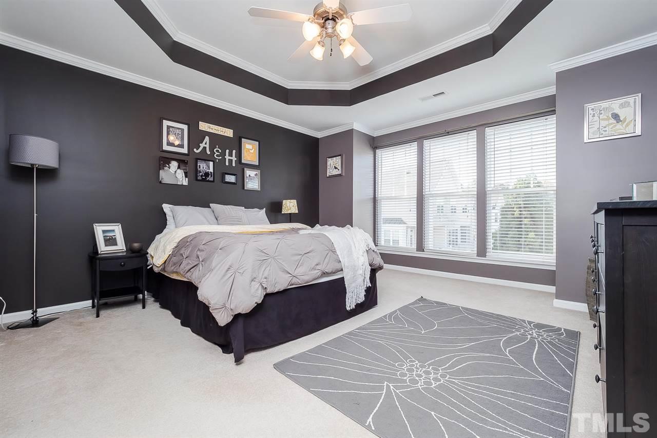5708 Cameo Glass Way Raleigh, NC 27612 - Photo 14 of 23 a bedroom with a large bed chandelier and a large window