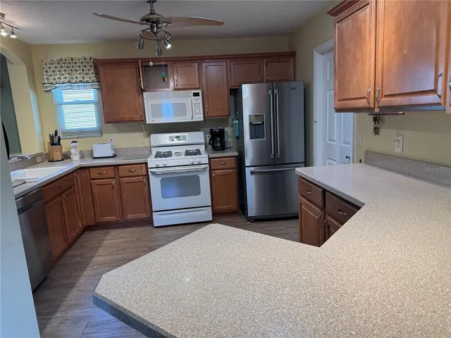 a kitchen with stainless steel appliances granite countertop a refrigerator a sink dishwasher a stove and a refrigerator