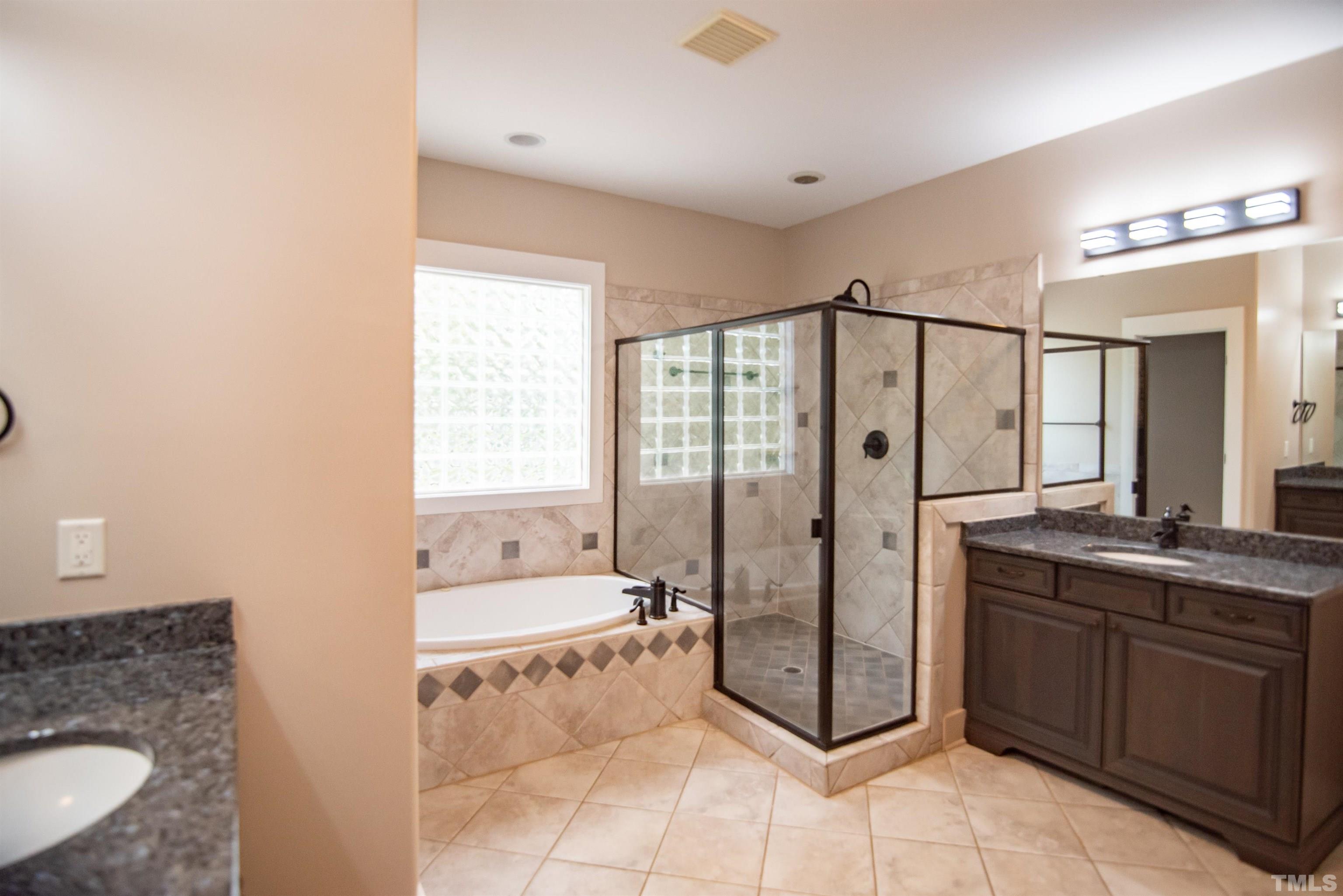 15004 Massimo Dr. Wake Forest, NC 27587 - Photo 14 of 27 a spacious bathroom with a granite countertop sink a mirror and a bathtub