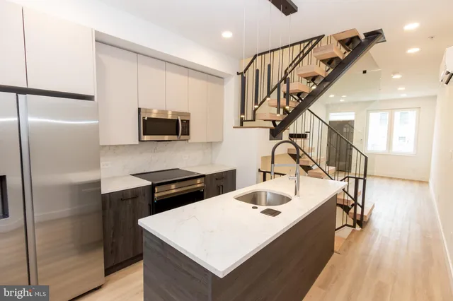 a kitchen with a refrigerator a sink dishwasher and a stove with wooden floor