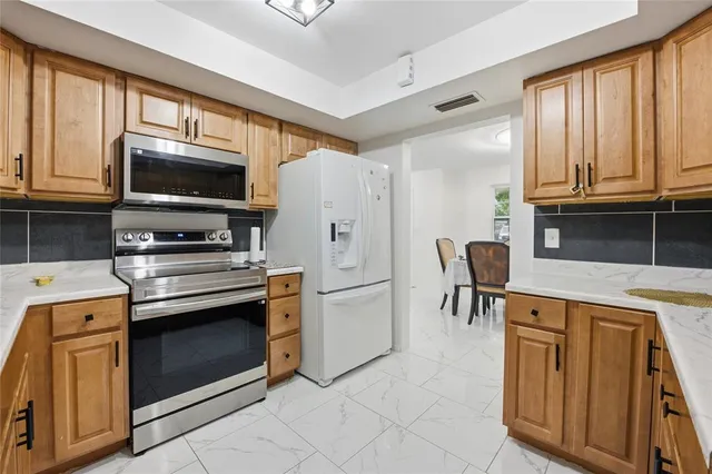 a kitchen with granite countertop a stove top oven microwave and refrigerator