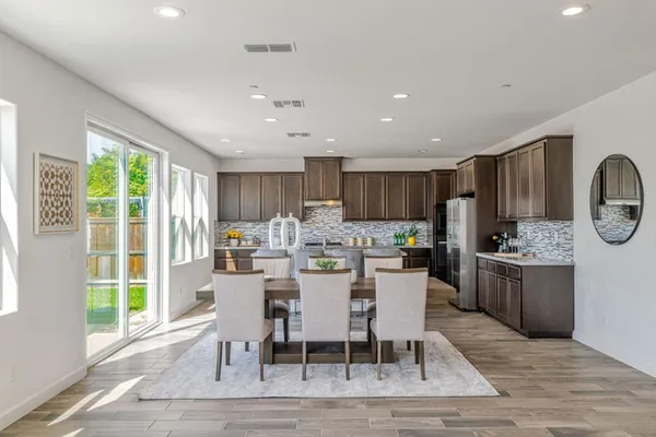 a kitchen with a dining table chairs and refrigerator