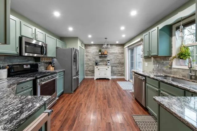 a kitchen with stainless steel appliances granite countertop a refrigerator a stove top oven a sink dishwasher and wooden cabinets with wooden floor