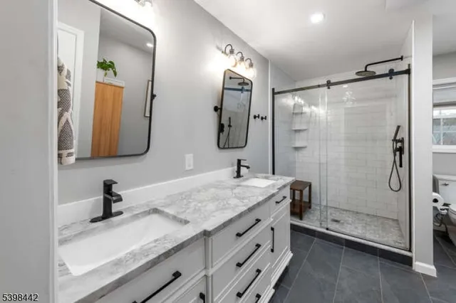 a bathroom with a granite countertop sink a mirror and shower
