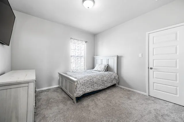 a room with a bed and a flat tv screen on the dresser