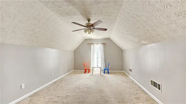 an empty room with chandelier fan and windows