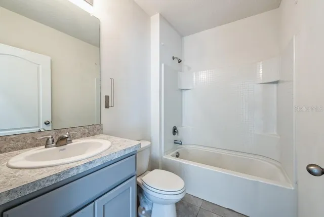 a bathroom with a granite countertop sink a toilet a mirror and bathtub