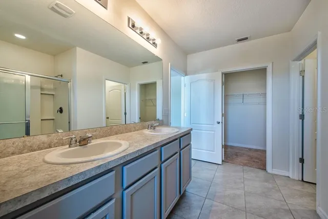 a bathroom with a granite countertop sink two mirror and shower