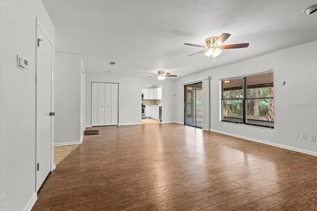 a view of an empty room with window and wooden floor