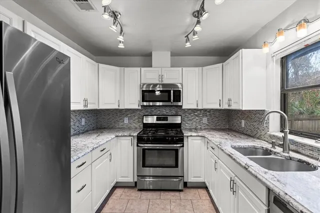 a kitchen with granite countertop a refrigerator stove and sink