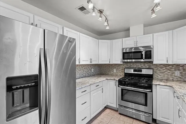 a kitchen with white cabinets and stainless steel appliances