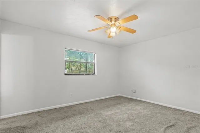 an empty room with a window and a fan