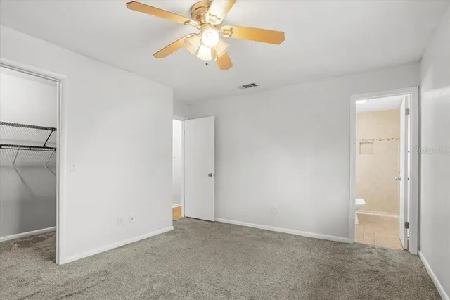 an empty room with closet and a chandelier fan