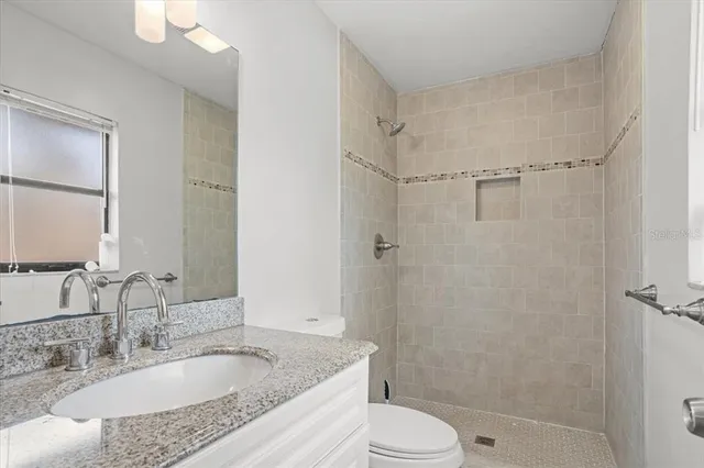 a bathroom with a granite countertop sink toilet and shower