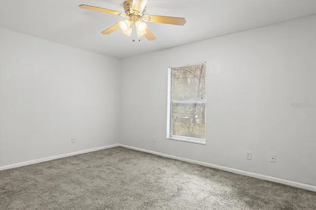 an empty room with a window and a fan