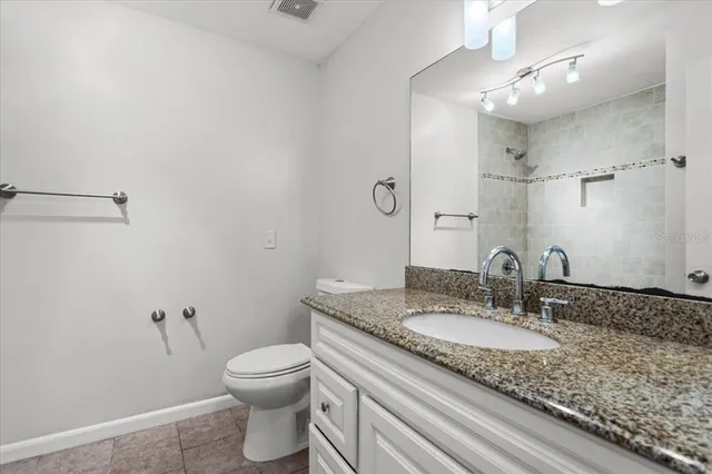 a bathroom with a granite countertop sink a toilet and a mirror