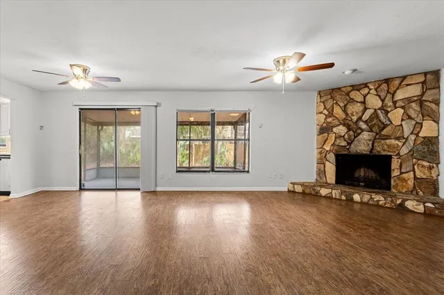 an empty room with windows fireplace and wooden floor