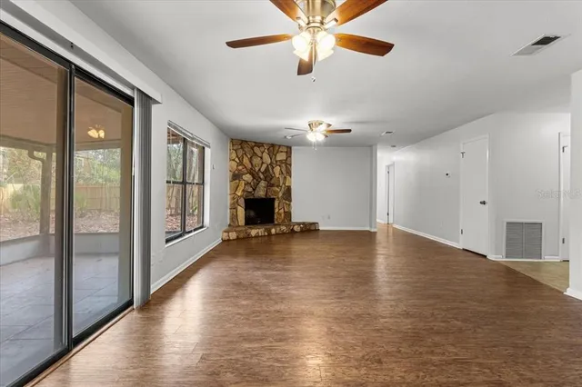 a view of an empty room with window and wooden floor