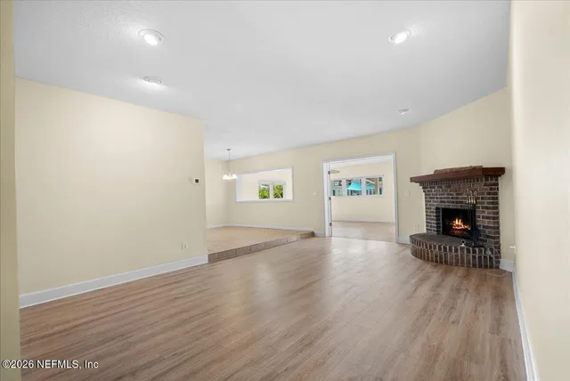 an empty room with wooden floor and a fireplace