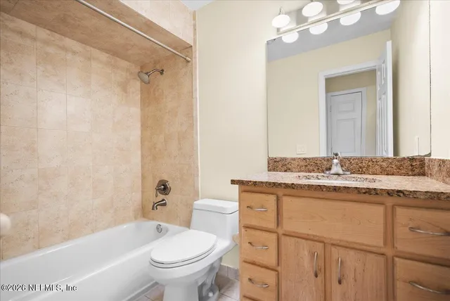a bathroom with a granite countertop toilet a sink and a bathtub