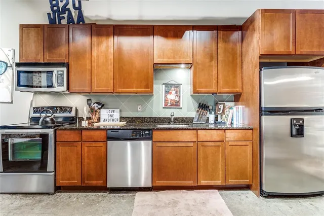 a kitchen with stainless steel appliances granite countertop a stove a sink and a refrigerator