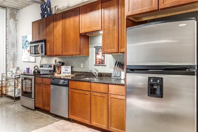 a kitchen with stainless steel appliances granite countertop a stove a sink and a refrigerator