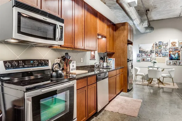 a kitchen with stainless steel appliances granite countertop a stove a sink and a microwave