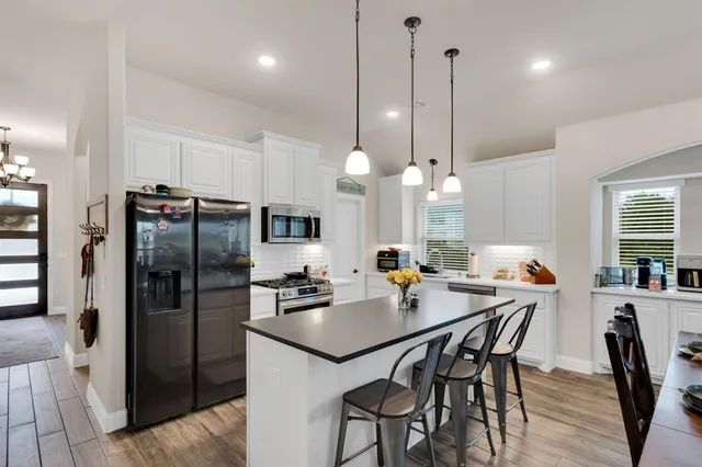 a kitchen with stainless steel appliances a dining table chairs sink and microwave
