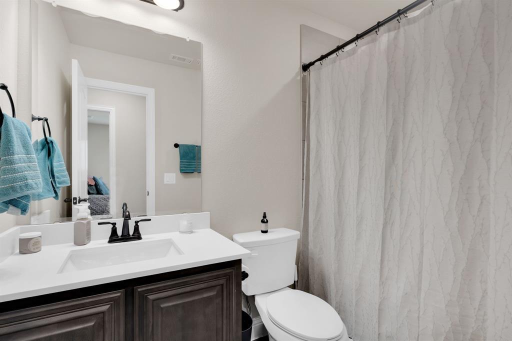 5038 Ridgehurst Lane Midlothian, TX 76065 - Photo 25 of 37 a bathroom with a sink a toilet a mirror and shower curtain