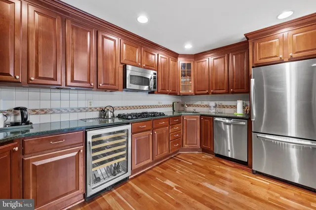 a kitchen with stainless steel appliances granite countertop a refrigerator a stove top oven a sink and dishwasher with wooden floor