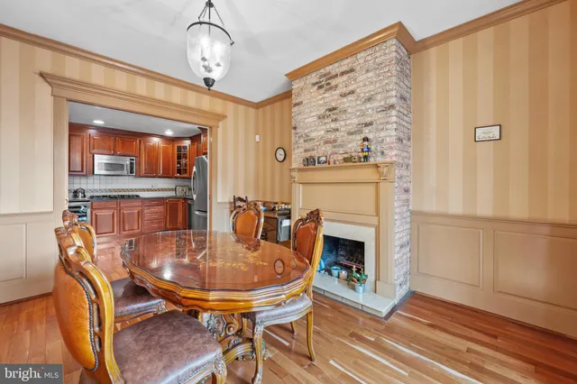 a dining room with wooden floor a chandelier a wooden table and chairs