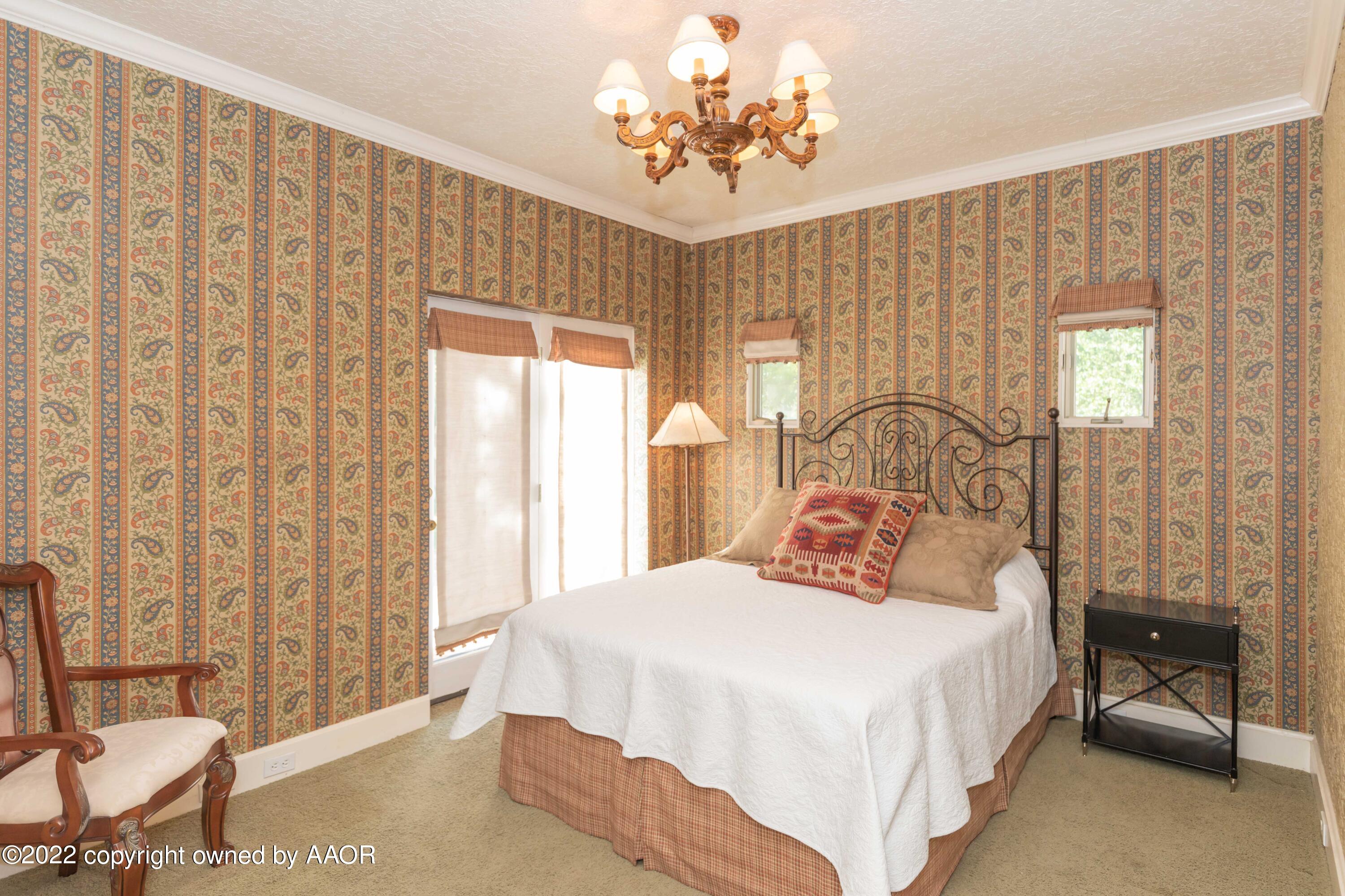 1607 South Harrison Street Amarillo, TX 79102 - Photo 38 of 71 a bedroom with a large bed and a chandelier